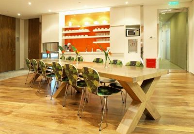 Bright communal kitchen and dining area featuring a wooden table with patterned chairs.
