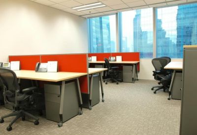 Modern open-plan office with red desk dividers and ergonomic chairs near large windows.