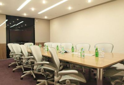 Professional boardroom with a long wooden table, white leather chairs, and bottled water.