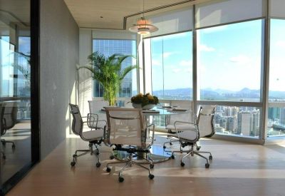 Communal breakout area with a round dining table, white chairs, and a large indoor plant.