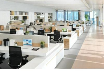 Spacious open-plan office with numerous white workstations and ergonomic black chairs.
