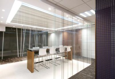 Sleek meeting room with high stools and glass partitions under a large recessed light.
