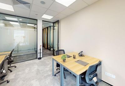 Internal two-person office suite with light wood desks and glass partitions.
