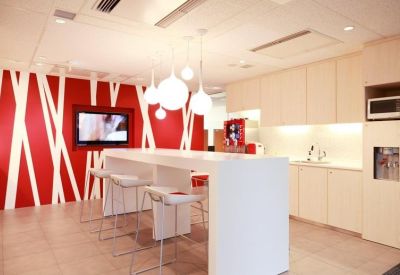 Communal break area with a red accent wall, white bar seating, and sphere pendant lights.