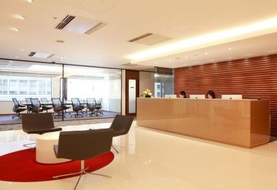 Modern reception lobby with a large wooden desk and lounge seating on a red rug.