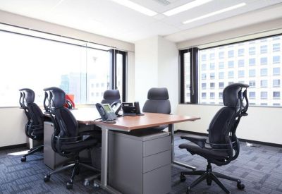 Sunlit private office with black ergonomic chairs and large windows.