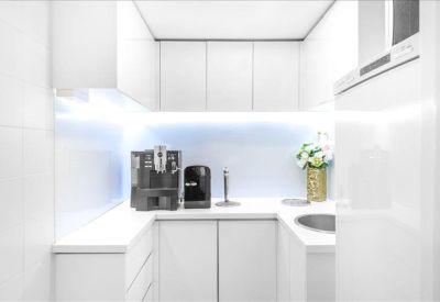 Clean white kitchen area with coffee machine and integrated cabinetry.