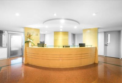 Bright reception area featuring a curved wood-panelled front desk and warm polished floors.