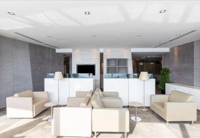 Contemporary communal lounge area with plush cream sofas and stylish grey paneling.