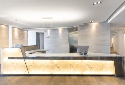 Sleek reception area featuring a large backlit marble front desk and modern lighting.