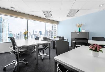 Bright private office with multiple workstations and floor-to-ceiling windows showing city views.