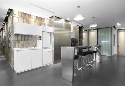 Modern communal kitchen with stainless steel island and white cabinetry.