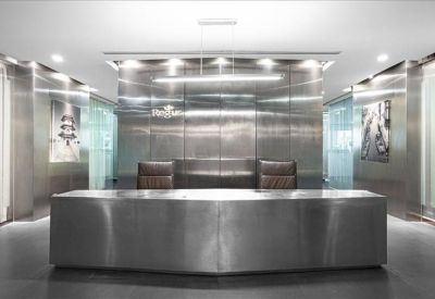 Minimalist reception area with a long brushed-metal desk and feature lighting.