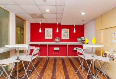 Communal break area with a vibrant red feature wall, high tables, and wood-look flooring.