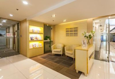 Bright reception waiting area with cream armchairs and built-in lit shelving for magazines.