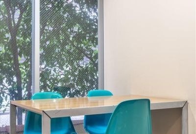 Workspace featuring a wooden desk and two teal modern chairs by a large window.
