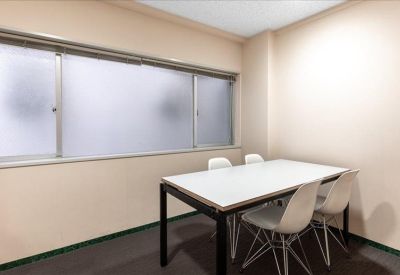 Bright four-person meeting room with a white table and frosted windows.
