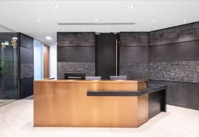 Sleek reception area with a metallic front desk against a dark textured feature wall.