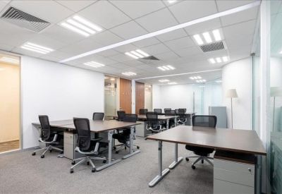 Spacious open-plan office with multiple workstations and bright overhead lighting.