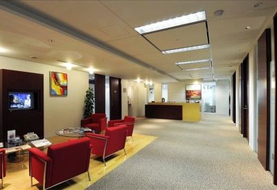 Lounge area with vibrant red armchairs and a reception desk in the distance.