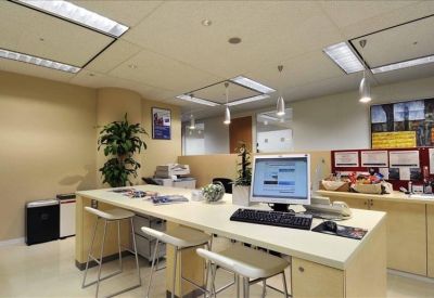 Open-plan coworking area with high-top tables, computers, and potted greenery.