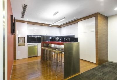 Modern communal kitchen area with wood floors, high bar seating, and white cabinetry.