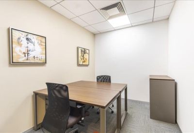 Small private office with wooden desks, black mesh chairs, and framed wall art.