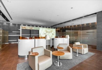Modern breakout area with white curved privacy pods, leather armchairs, and small wooden coffee tables.