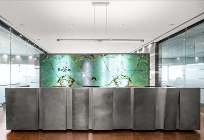 Minimalist reception desk with a textured metallic facade and a glowing green backlit marble feature wall.