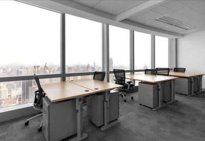 Spacious open-plan workspace featuring rows of light wood desks along a panoramic window wall.