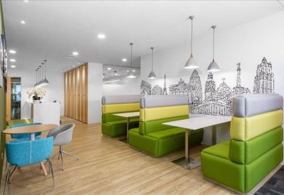Vibrant communal lounge with green and yellow booth seating and a decorative city skyline mural.
