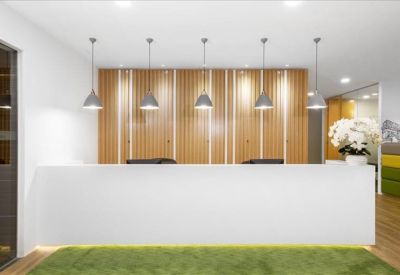 Sleek white reception desk with modern pendant lighting and a wooden feature wall.