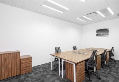 Brightly lit team office featuring wooden desks and ergonomic mesh chairs.
