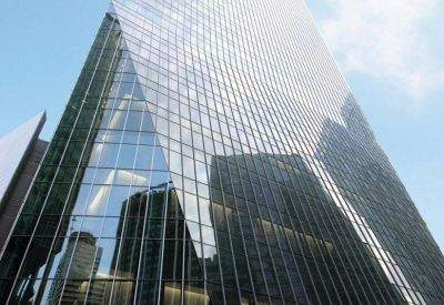 Exterior view of the soaring glass facade of One Raffles Quay North Tower against a blue sky.