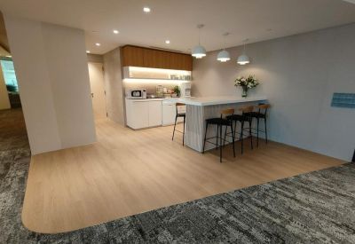 Modern office pantry and break area with a white marble island and wooden cabinetry.