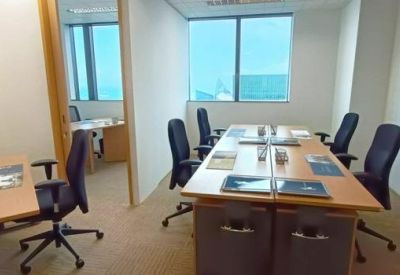 Four-person private office with wooden desks and blue ergonomic chairs.