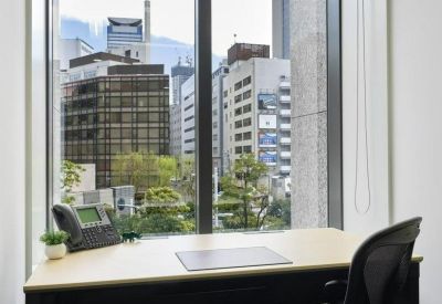 Bright private office desk situated next to a large window with city views.