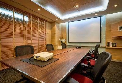 Professional meeting room with a large wooden conference table and projection screen.