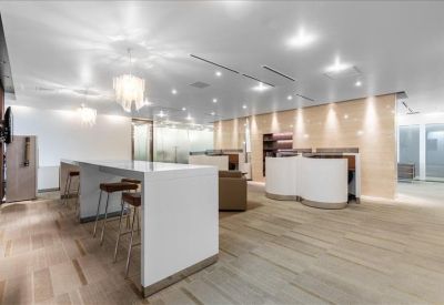 Modern communal breakout area with high-top seating and warm wood flooring.