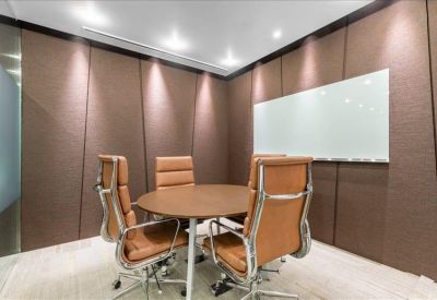 Small meeting room with round table, brown leather chairs, and whiteboard.