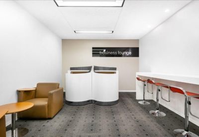 Lounge area with a leather armchair, side tables, and sleek white partitions.
