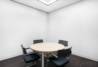Small private meeting room with a round table and four black chairs.