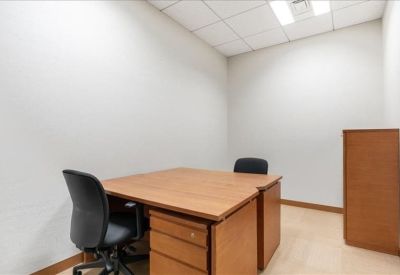 Private two-person internal office suite with wood desks and black ergonomic chairs.