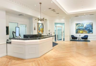 Bright reception area with a white marble desk and herringbone wood flooring.