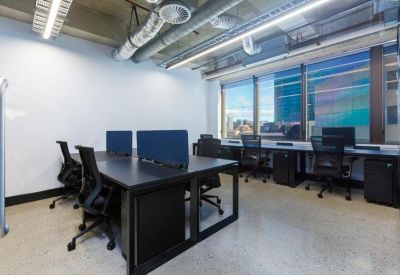 Industrial style workspace with long black desks and exposed ceiling pipes.