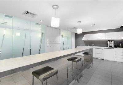 Sleek communal kitchen and breakout area with a long breakfast bar and modern stools.