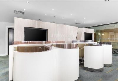 Contemporary reception area featuring white curved desks and built-in monitors.