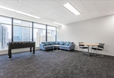 Spacious breakout area with a blue L-shaped sofa, coffee table, and foosball table.