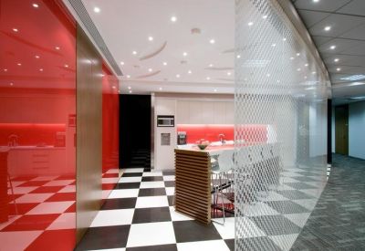 Modern communal kitchen and breakout area featuring red feature walls and a checkered floor.