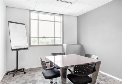 Bright breakout room with a square table, white chairs, and a mobile whiteboard.